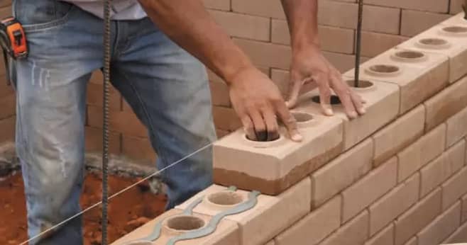 Imagem de um homem ascentando tijolos ecológicos em uma parede